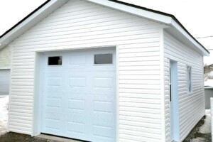 Dalle de béton de 6’’. Revêtement extérieur en vinyle Gentek avec coin de vinyle. Soffite de 12’’ et fascia 6’’ en aluminium blanc. <br>
Toit standard, pente 5/12 en bardeaux d’asphalte IKO. Porte de garage en acier modèle Premium (3 colonnes x 4 rangées) – blanc 9’ x 7’avec 2 fenêtres claires dans le haut, isolée R-16. 
<br>
Fenêtre coulissante PVC – blanc 36’’x 39’’ sur le côté et arrière. Porte de service en acier – blanc 34’’ x 82’’avec fenêtre guillotine. Garage Le Standard, 16' x 20' x 8'