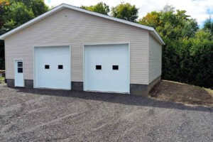 Dalle de béton 8’’ avec retour de fondation de 24’’. Revêtement extérieur en vinyle Gentek avec coin de vinyle. Soffite de 12’’ et fascia de 6’’en aluminium blanc. Toit standard, pente 5/12 en bardeaux d’asphalte IK0. 2 portes de garage en acier modèle Urbain-blanc 10’ x10’ avec fenêtres dans le panneau du centre incluant moteur électrique, isolée R-16. Fenêtre aluminium 60’’x48’’ à battant. Une porte de service standard en acier - blanc 34’’ x 82’’avec fenêtre à guillotine en façade du garage. Garage Commercial - Le Jumeau, 36' x 30' x 10'