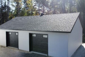 Dalle de béton monolithique .Revêtement extérieur en vinyle Gentek avec coin de vinyle. Soffite de 12’’ et fascia de 6’’en aluminium noir. Toit standard, pente6/12inverséen bardeaux d’asphalte IK0.2 portes de garage en aciermodèlePremium-noir8’ x 7’ avec fenêtres dans le haut, isolée R-16. Fenêtre coulissante PVC noir-36’’x 39’’et une porte de service standard en acier-noir34’’ x 82’’. Garage Le Jumeau, 24' x 36' x 8'