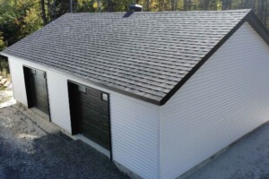 Dalle de béton monolithique .Revêtement extérieur en vinyle Gentek avec coin de vinyle. Soffite de 12’’ et fascia de 6’’en aluminium noir. Toit standard, pente6/12inverséen bardeaux d’asphalte IK0.2 portes de garage en aciermodèlePremium-noir8’ x 7’ avec fenêtres dans le haut, isolée R-16. Fenêtre coulissante PVC noir-36’’x 39’’et une porte de service standard en acier-noir34’’ x 82’’. Garage Le Jumeau, 24' x 36' x 8'